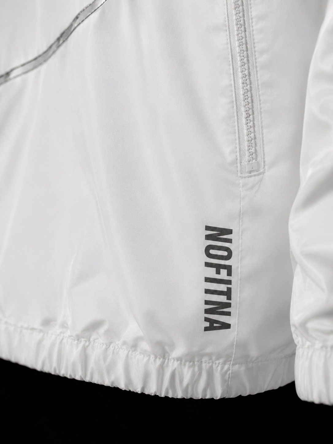 Wordmark NO FITNA réfléchissant sur veste blanche, détail